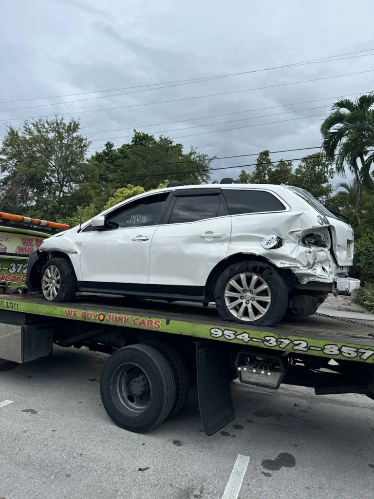 A damaged white SUV on a flatbed tow truck promoting Cash For Junk Car In Hollywood FL