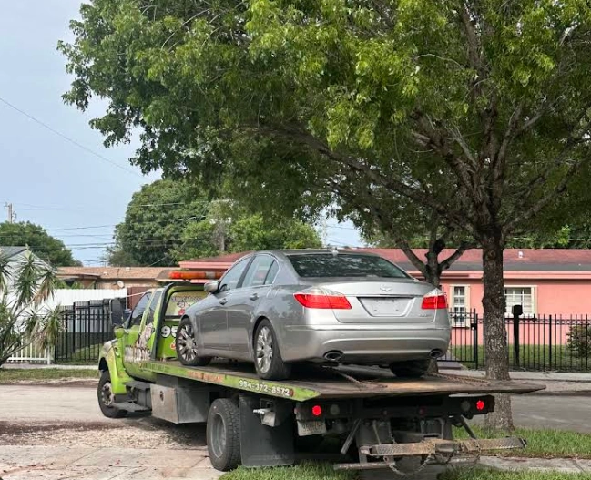 A sedan on a flatbed tow truck representing vehicle buyers in Broward County FL