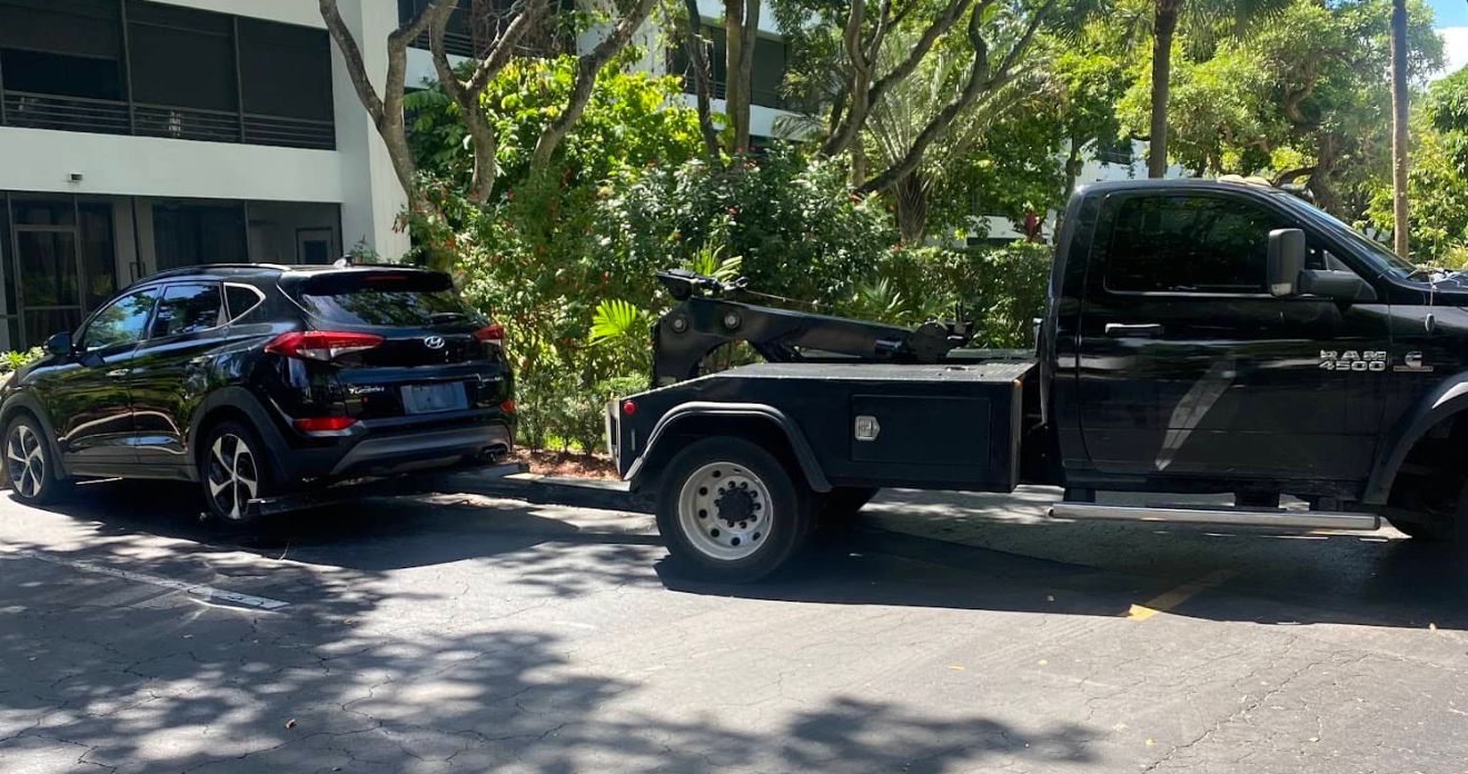 An SUV being towed by a tow truck representing junk car removal Sunrise FL