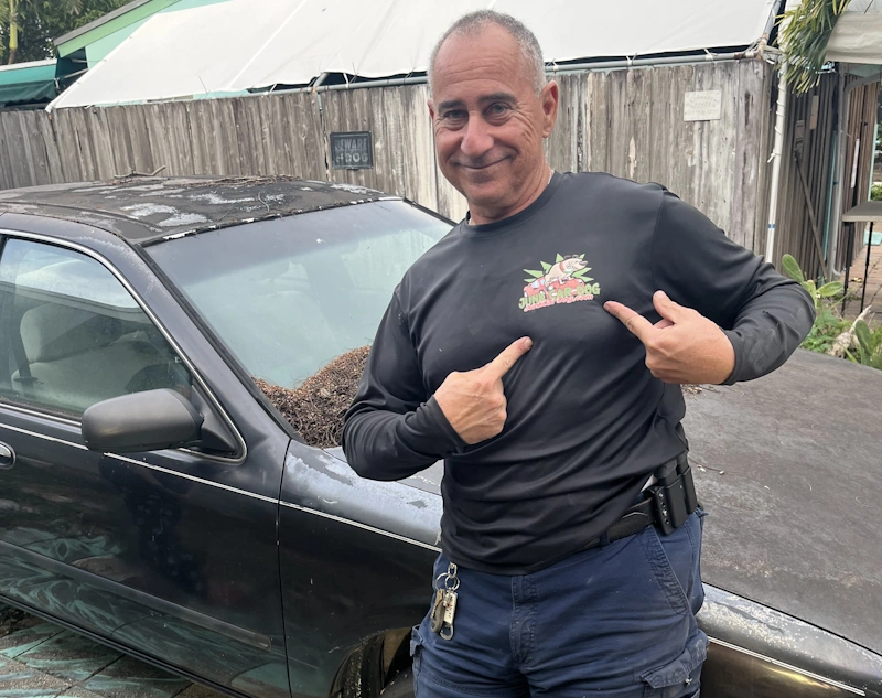 A person stands next to a black car for Cash for Junk Cars in Pompano Beach