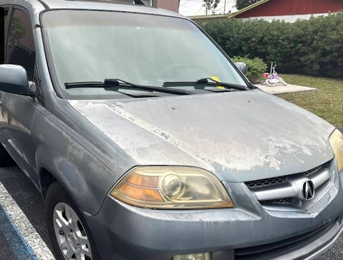 Front view of a junk 2006 Acura MDX in Margate FL with significant paint oxidation on the hood and yellowed headlights, illustrating a vehicle ready for junk car removal for cash.