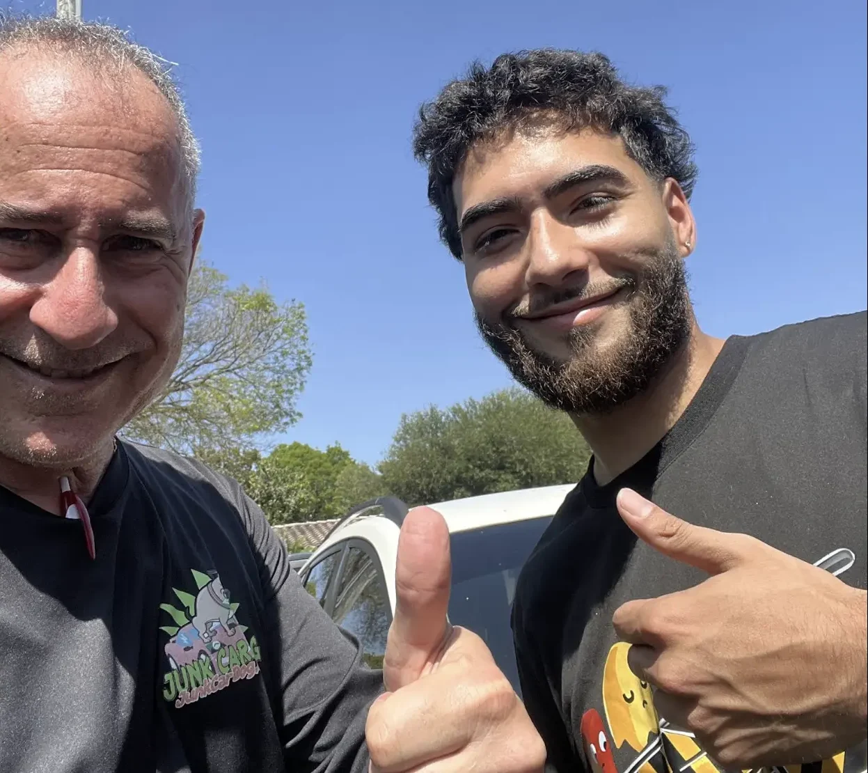 A satisfied customer standing outside next to a professional buyer after finalizing a deal to sell a damaged Nissan Rogue in Hollywood.